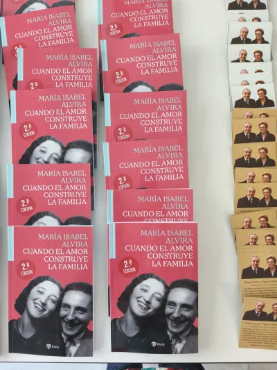 Ejemplares del libro Cuando el amor construye la familia de María Isabel Alvira y estampas de oración expuestos sobre una mesa