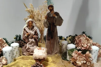 Primer plano de un tradicional belén navideño con figuras y velas decorativas.