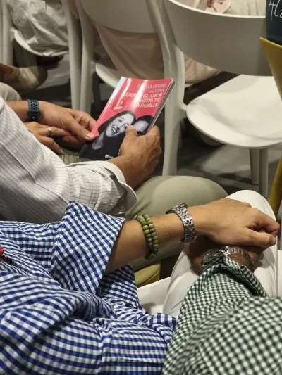 Asistentes en sus asientos sosteniendo un ejemplar del libro