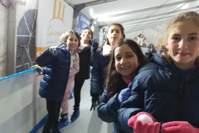 Primer plano de un grupo de cinco niñas del club sonriendo a la cámara mientras están en la pista de hielo.