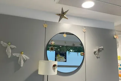 Decoración navideña: estrellas, ángeles de papel y un espejo redondo.
