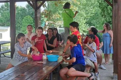 Chicos jugando en una mesa con madres alrededor