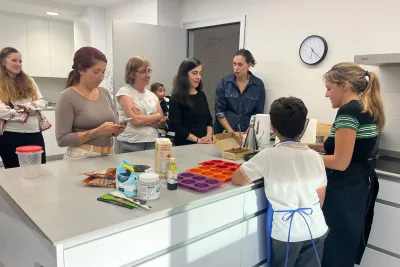 Varias señoras en la cocina mirando cómo se prepara la masa de los donuts.