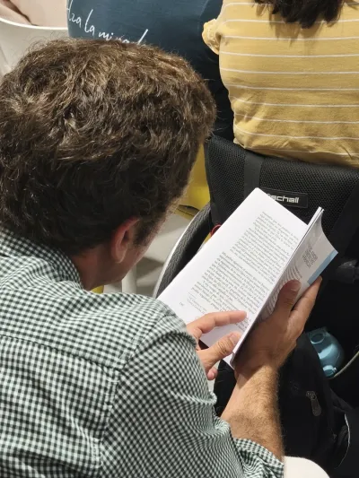 Un asistente leyendo las páginas interiores del libro durante la presentación