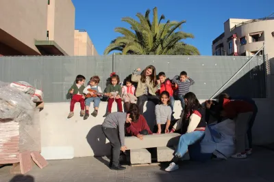 Grupo de chicos al sol, sentados junto a la valla