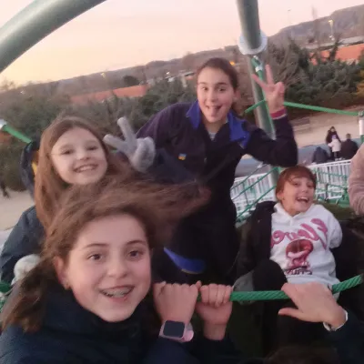 Primer plano de cuatro niñas divirtiéndose y haciendo gestos de victoria en una red de escalada.