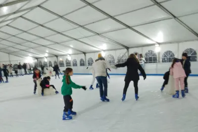 Niñas del club patinando en la pista cubierta. Una de ellas está aprendiendo con la ayuda de un adulto.