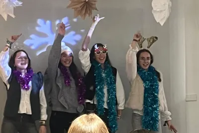 Cuatro jóvenes en el escenario bailando con accesorios y decoración festiva.