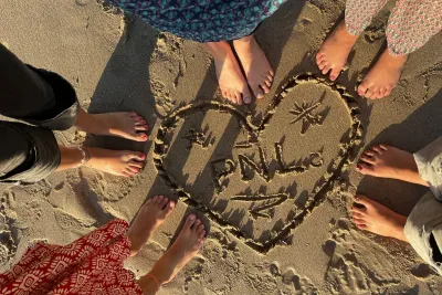 Corazón en la arena con pies alrededor