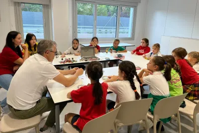 Grupo de chicas sentadas alrededor de las mesas trabajando en los pendientes.
